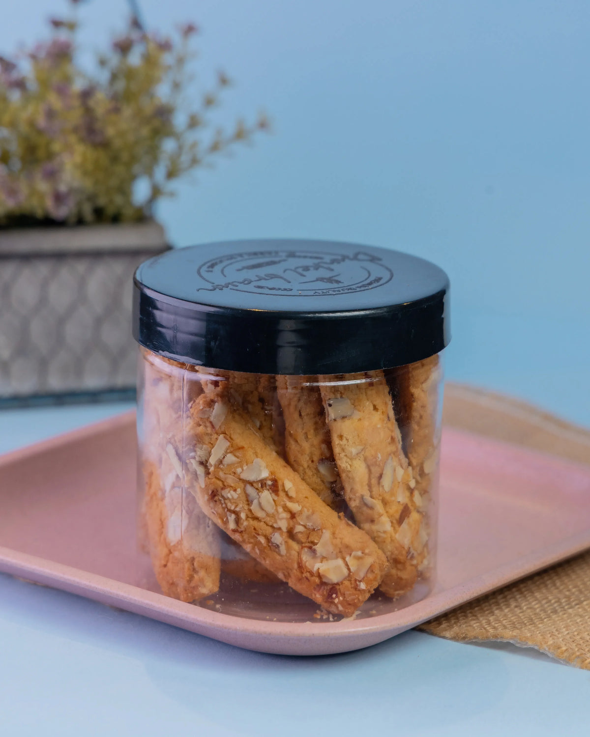 A Dunkel Braun jar of almond biscotti-style rusks on a pink tray
